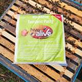 A green package of HiveAlive Fondant Patty placed on a wooden surface with bees around it.
